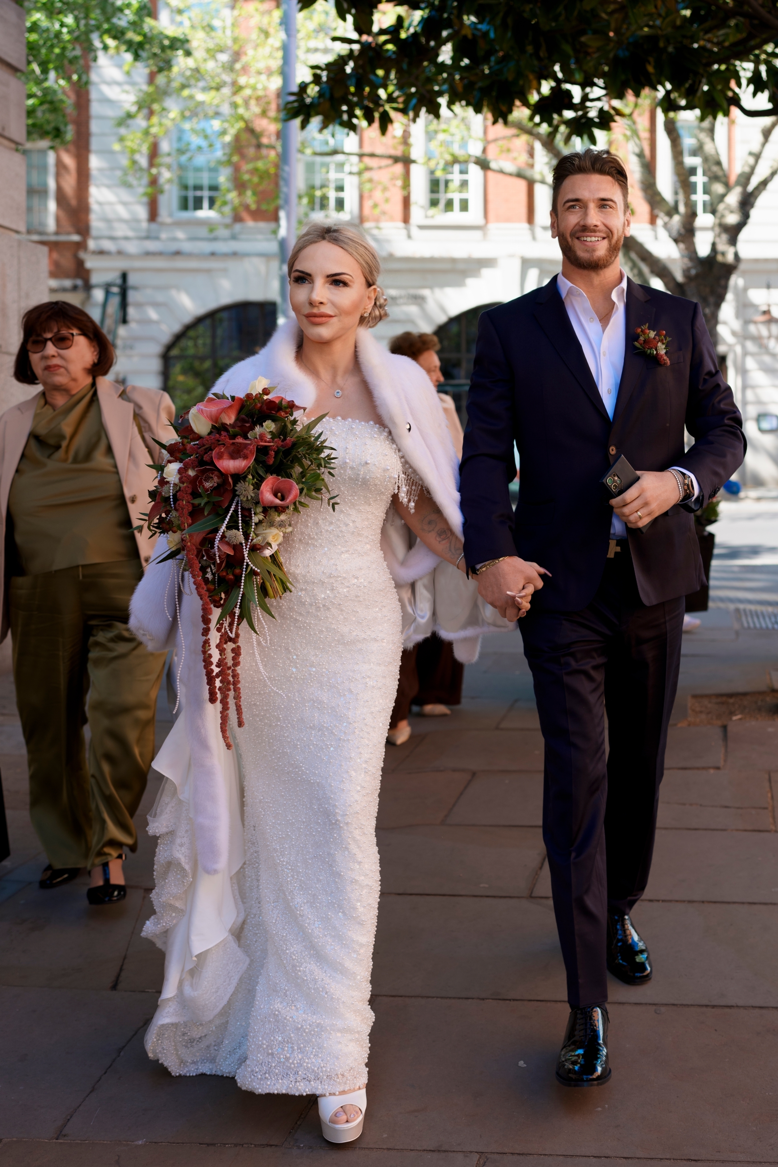 Joyful bride and groom exit Chelsea Old Town Hall, hand-in-hand.