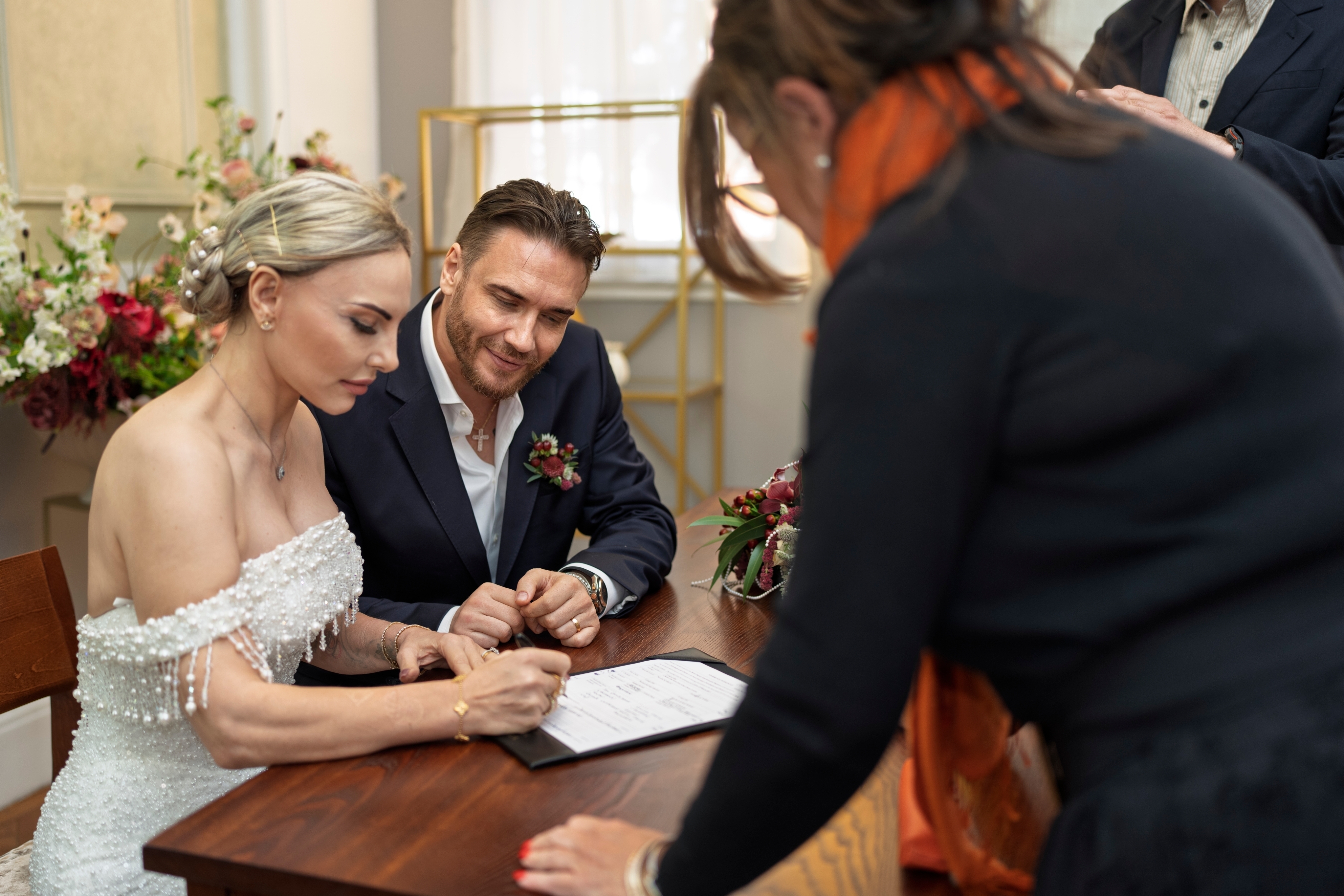The beautiful bride signing the register with her smiling groom beside her.